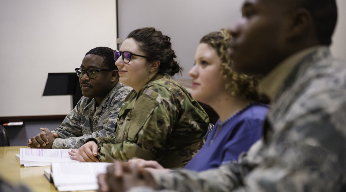 Four students in classroom, three in military fatigues. 