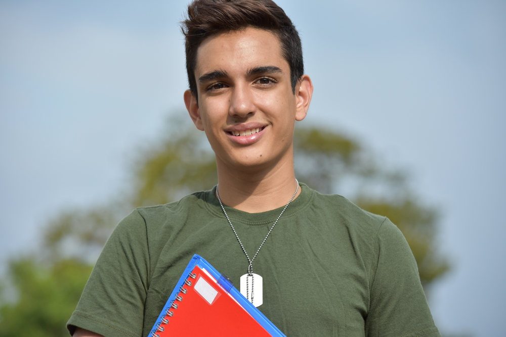 Student looking at the camera smiling and holding a notebook. 