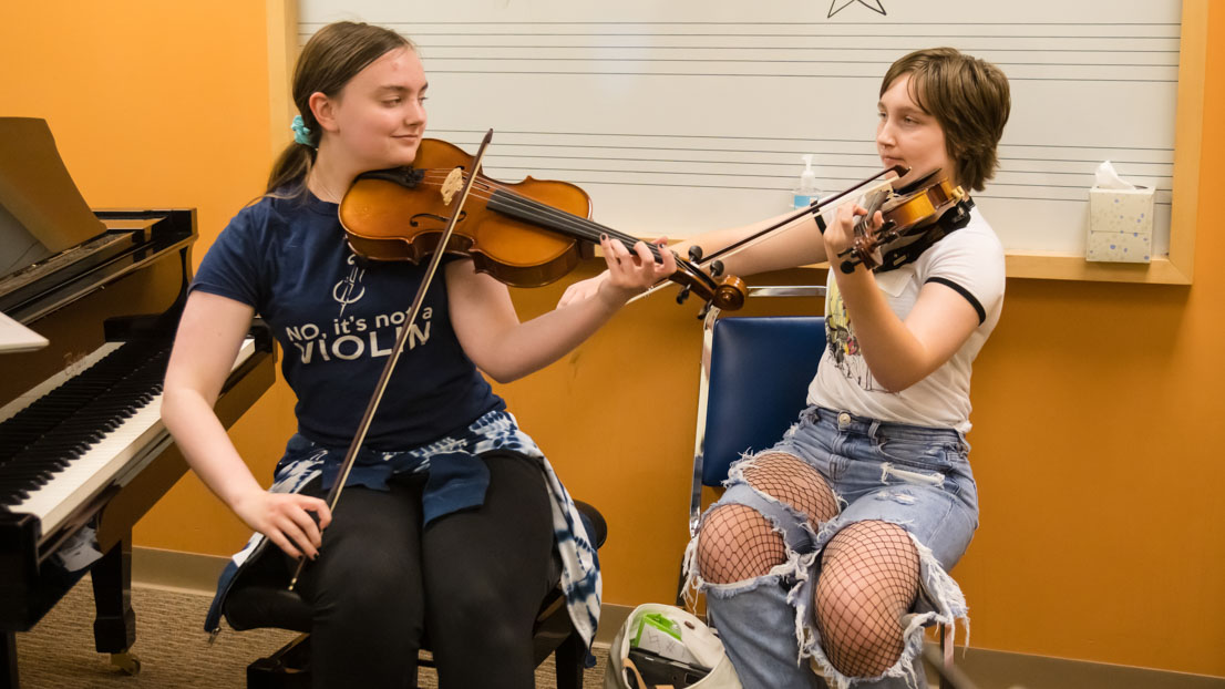 Two students playing violins together.
