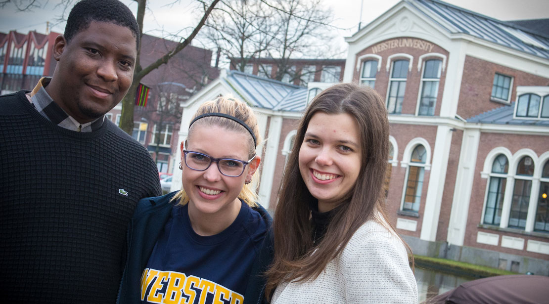 Three students stand in front of one of the buildings at our Leiden campus.