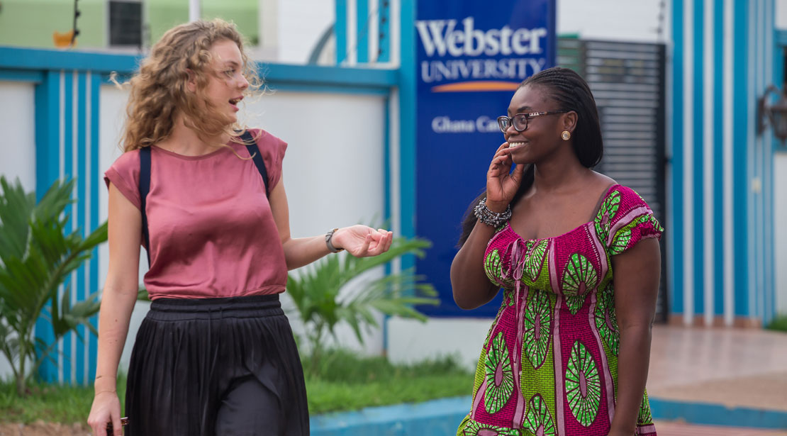 Two students walk in front of the entrance to our Ghana campus.