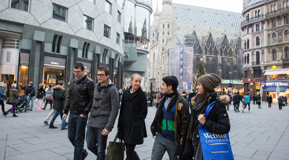 A group of students walks together through a public plaza in Vienna.