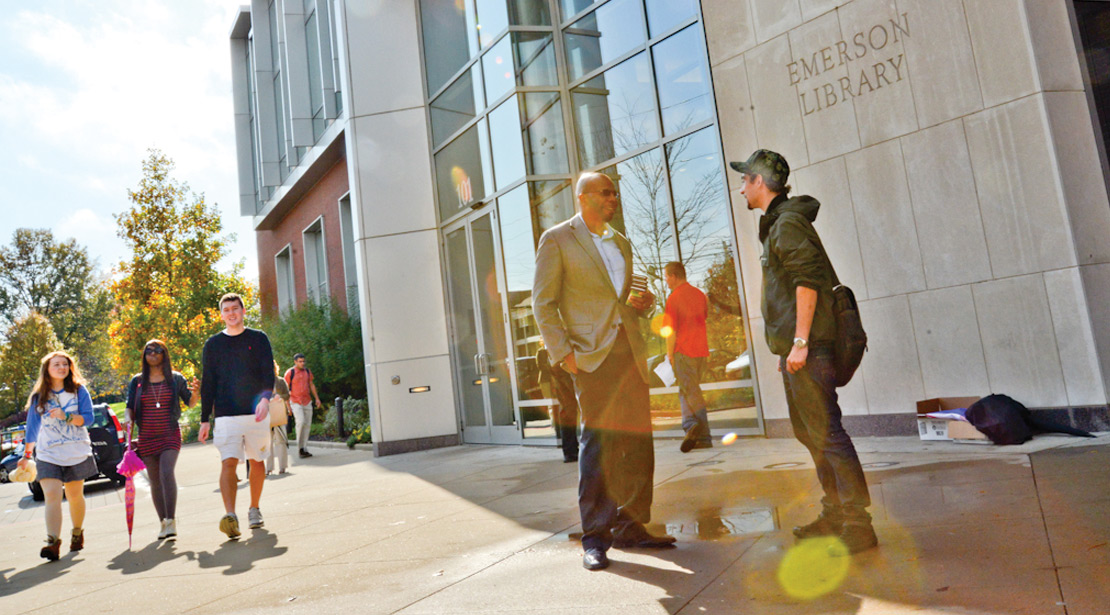 Photo of students walking and others standing and talking in front of Webster University building