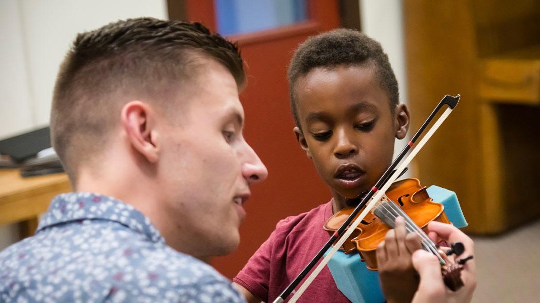 A young student is taught violin in the Community Music School.