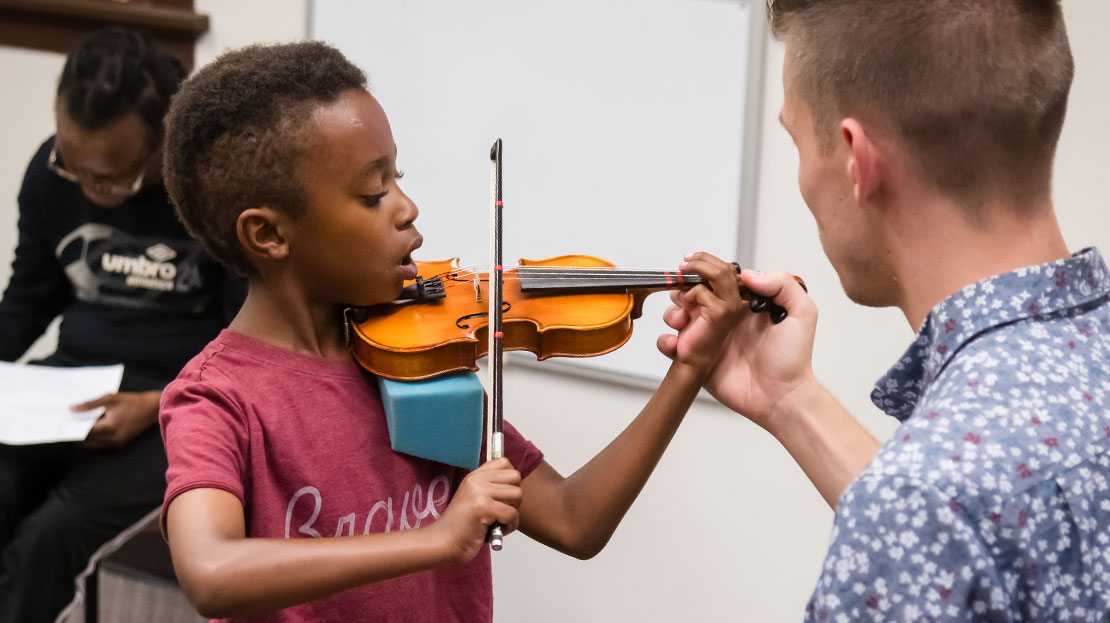 A young student is taught violin in the Community Music School.