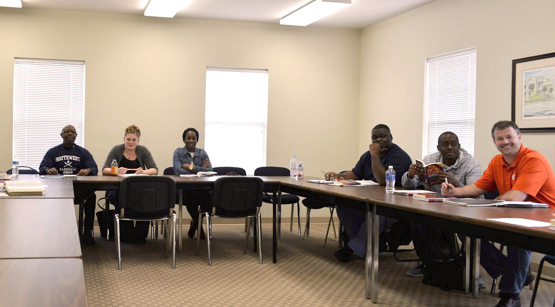 Two groups of three students sitting along two sides of rows of tables forming a large rectangle.