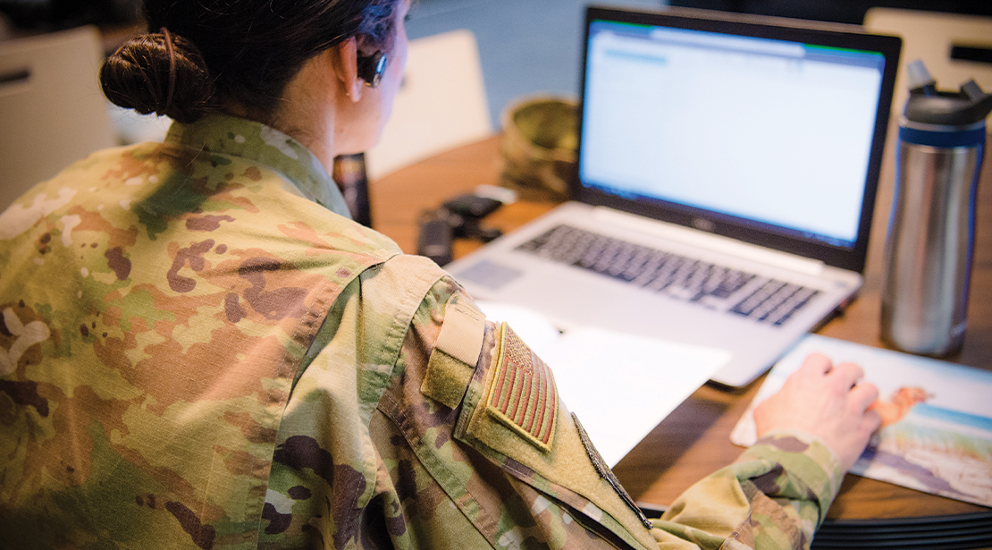 Female student with headphones working at a laptop on an online class. 