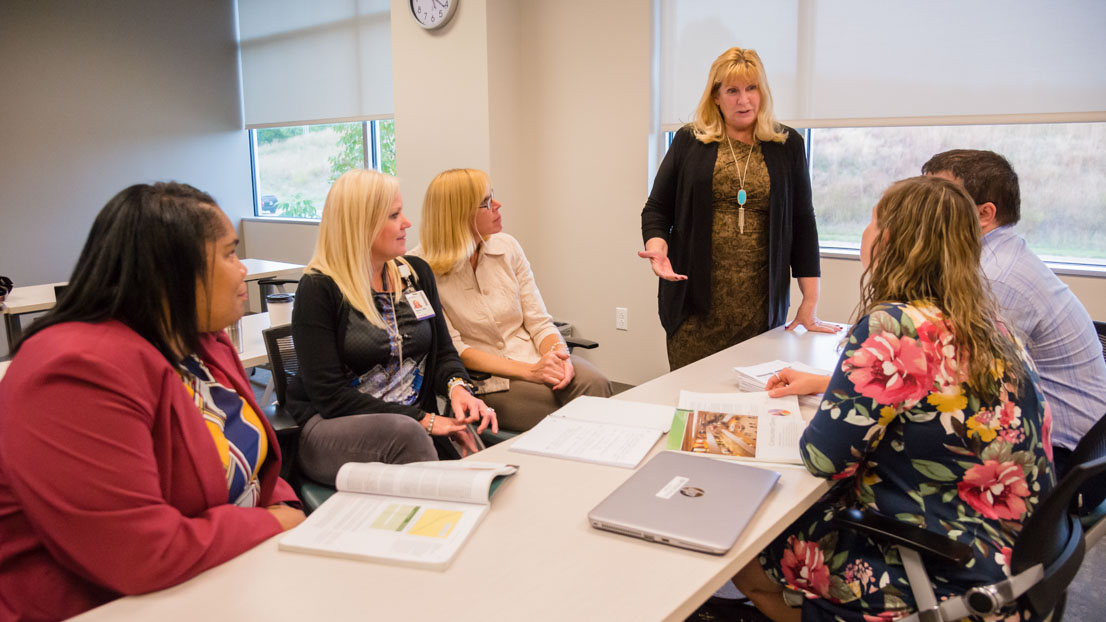 A group of five students discussing economic analysis with their professor