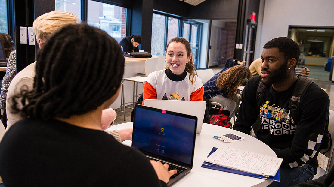 Four students study together with laptops.