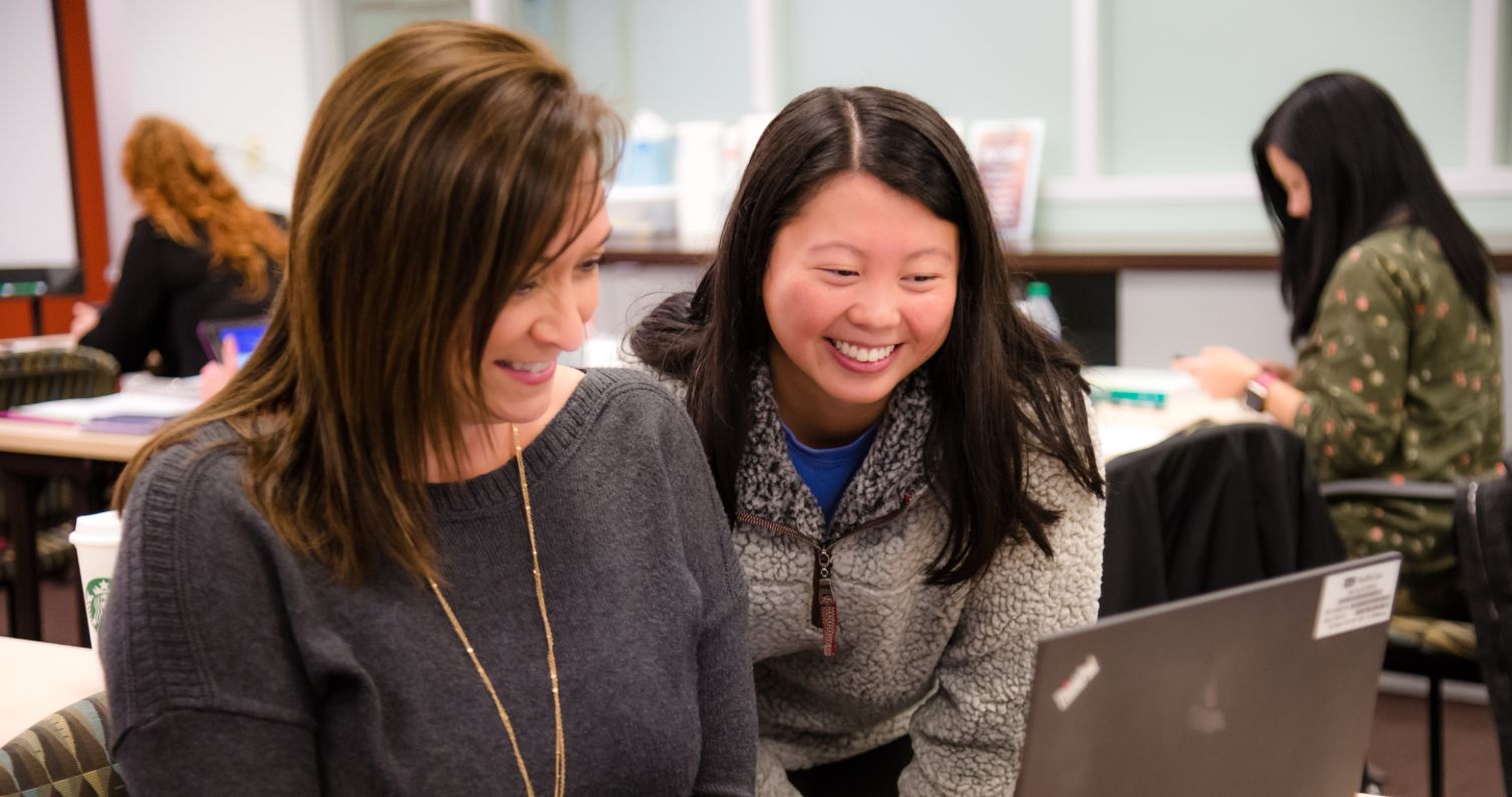 Students looking at laptop and smiling