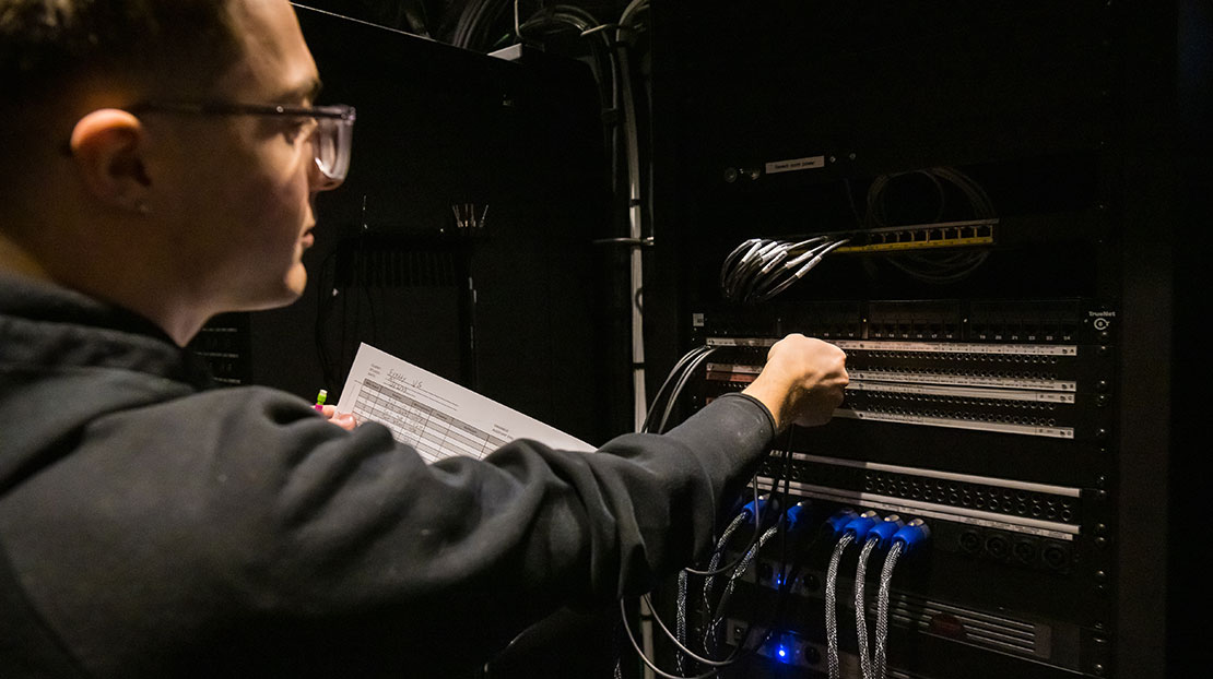 student uses wiring sheet to make sound cable connections