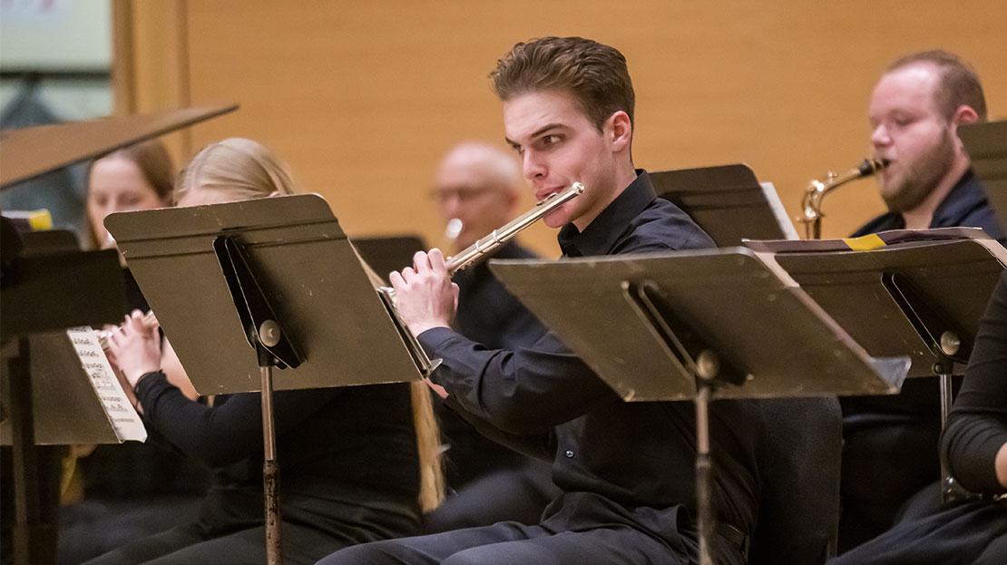 Student plays a flute accompanied by other instrumentalists during a Webster University Wind Ensemble concert.
