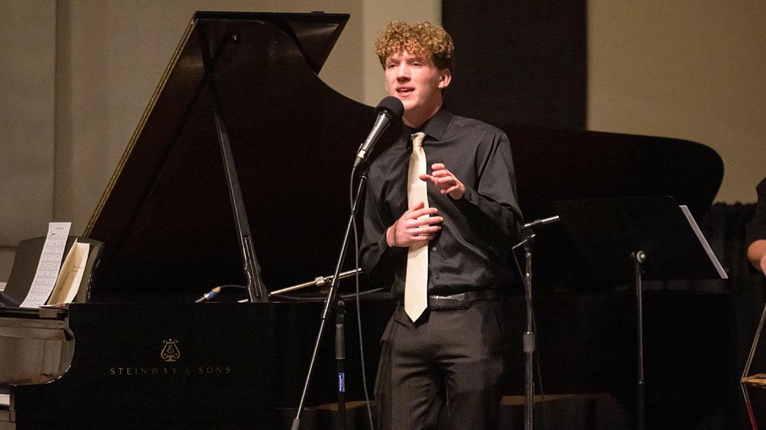 A student vocalist performs live on stage with the Webster University Jazz Singers ensemble.