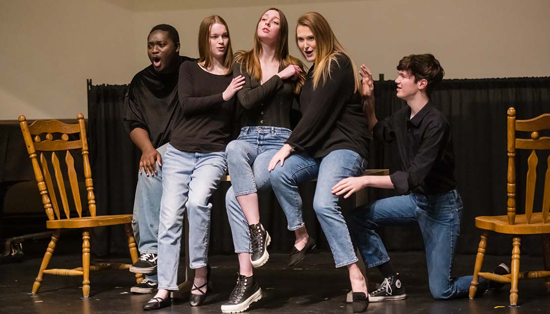 A group of students singing during a performance by Webster University Opera Studio.