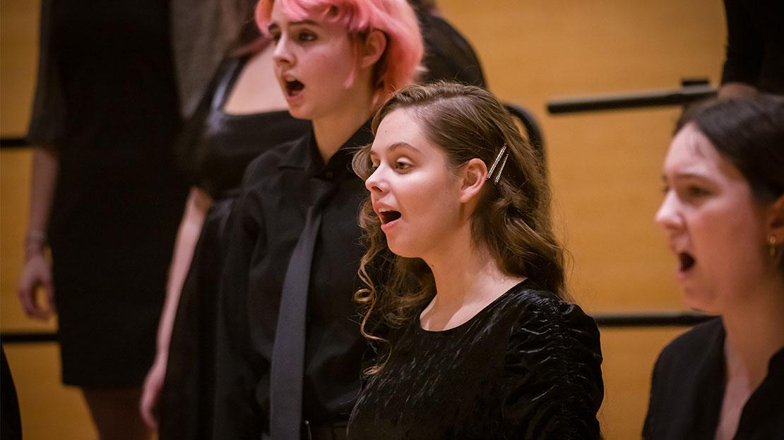 Student vocalists perform together on stage as part of a Webster University choral concert.