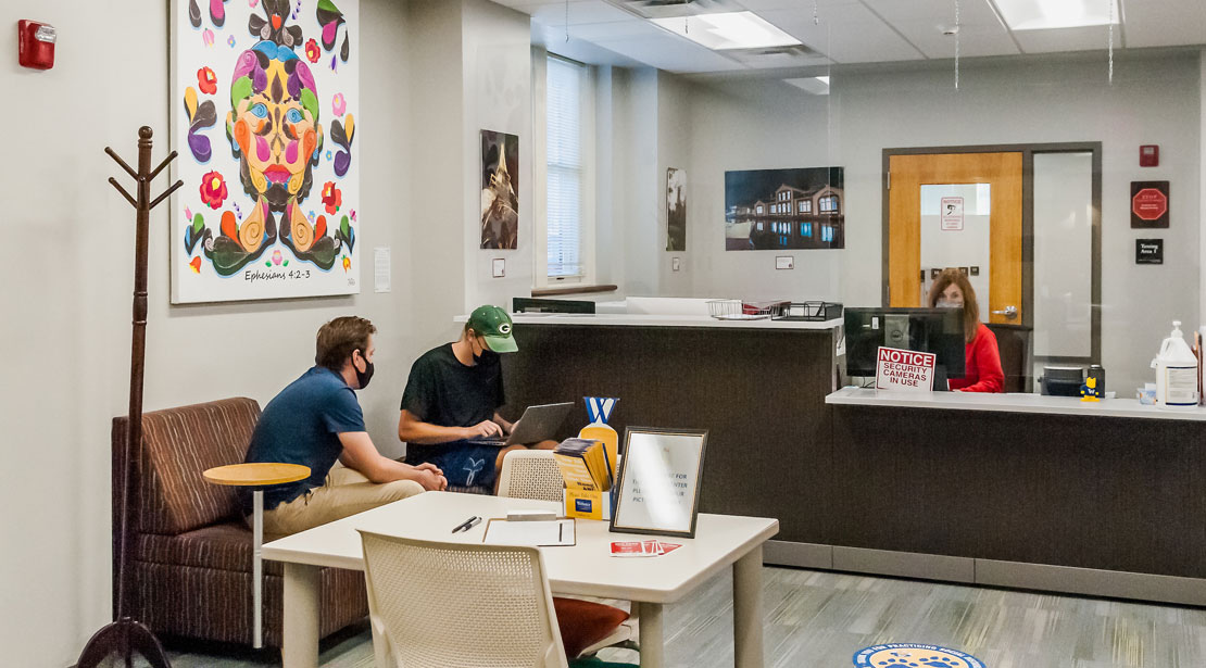 Through the second Reeg Academic Resource Center entrance is the lobby to the Testing Center with a reception desk and a table with two chairs in front of it.