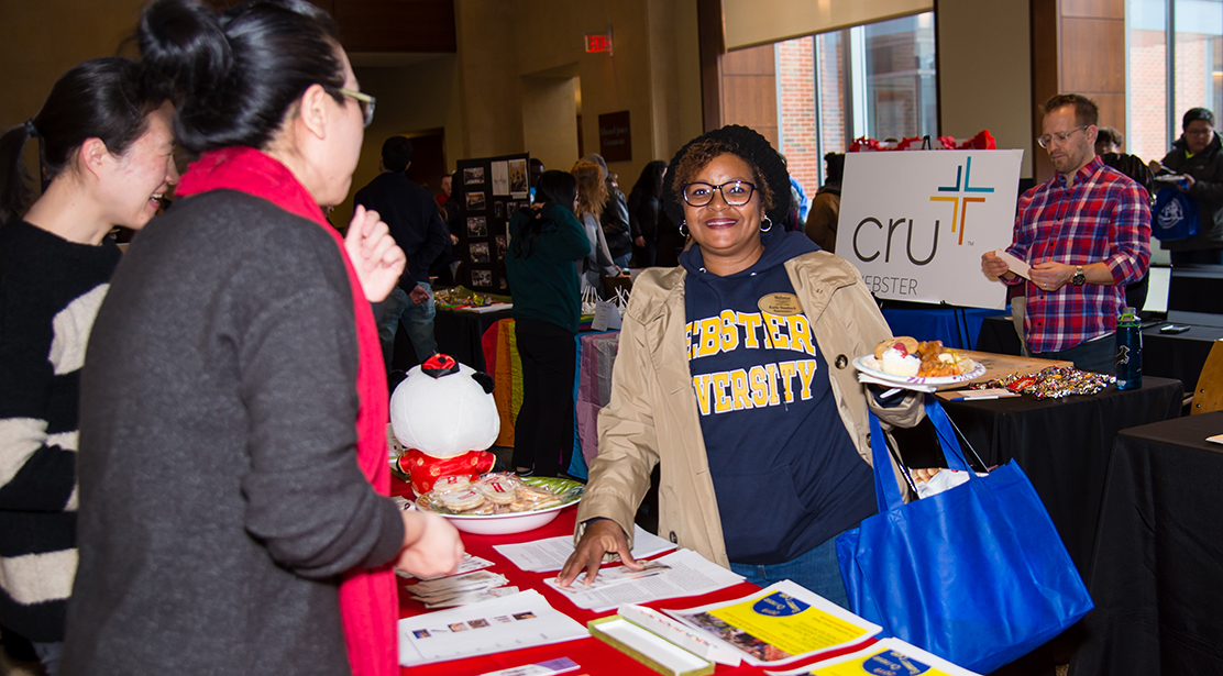 attendee holding plate of food picking up information from a conference display table