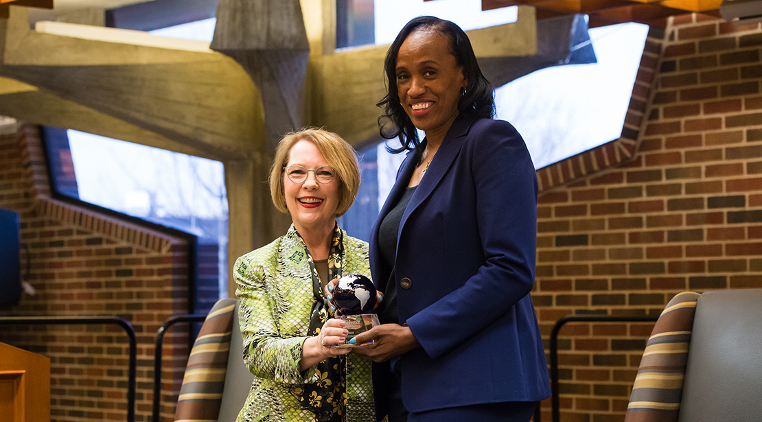 Chancellor Beth Stroble hands Olympian Jackie Joyner-Kersee a globe-shaped award.