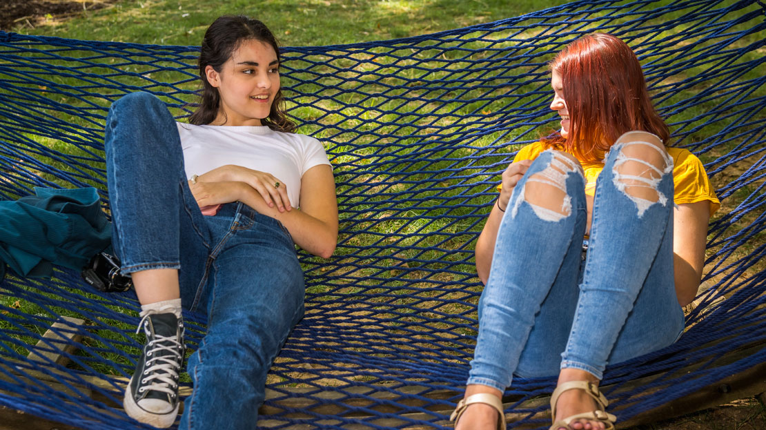 Two young students on a hammock together.