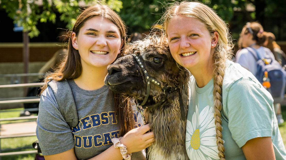 Two female students pose with an alpaca.