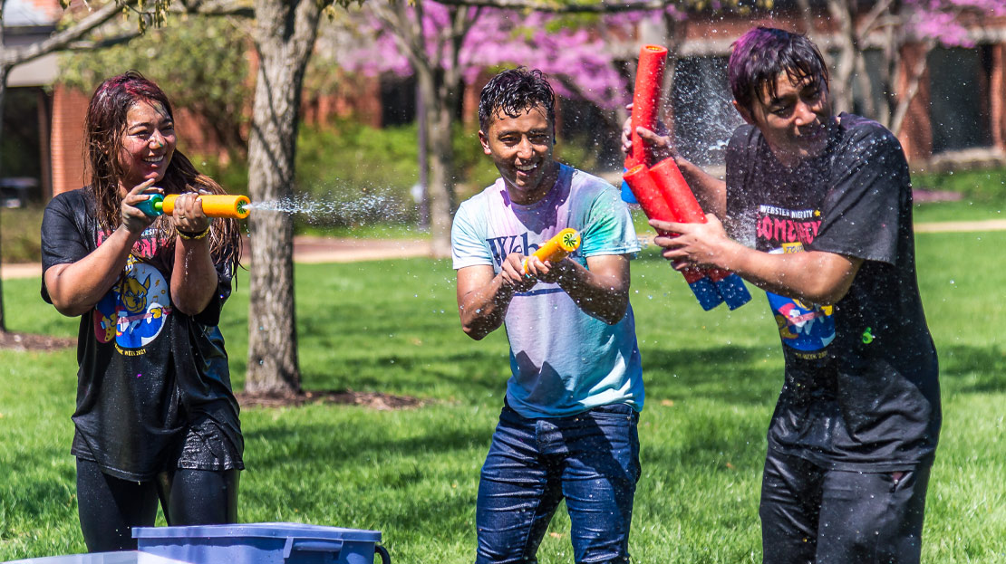 Three students play and laugh during the Holi festival.