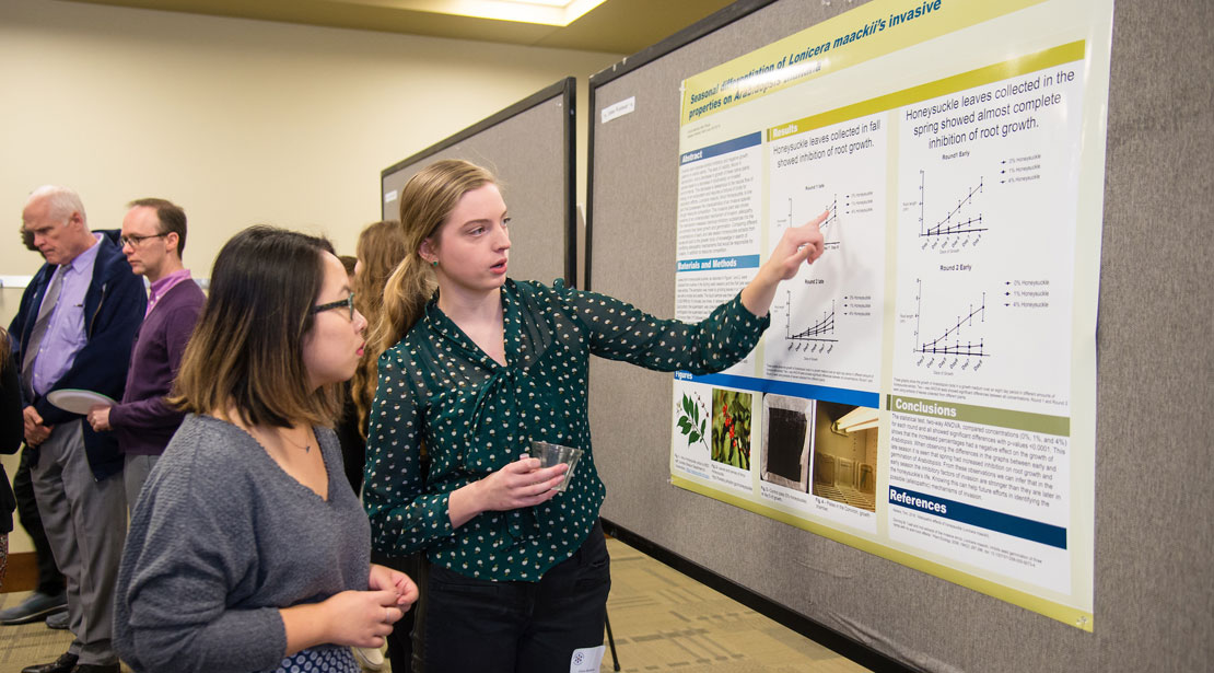 student explaining research results shown on poster
