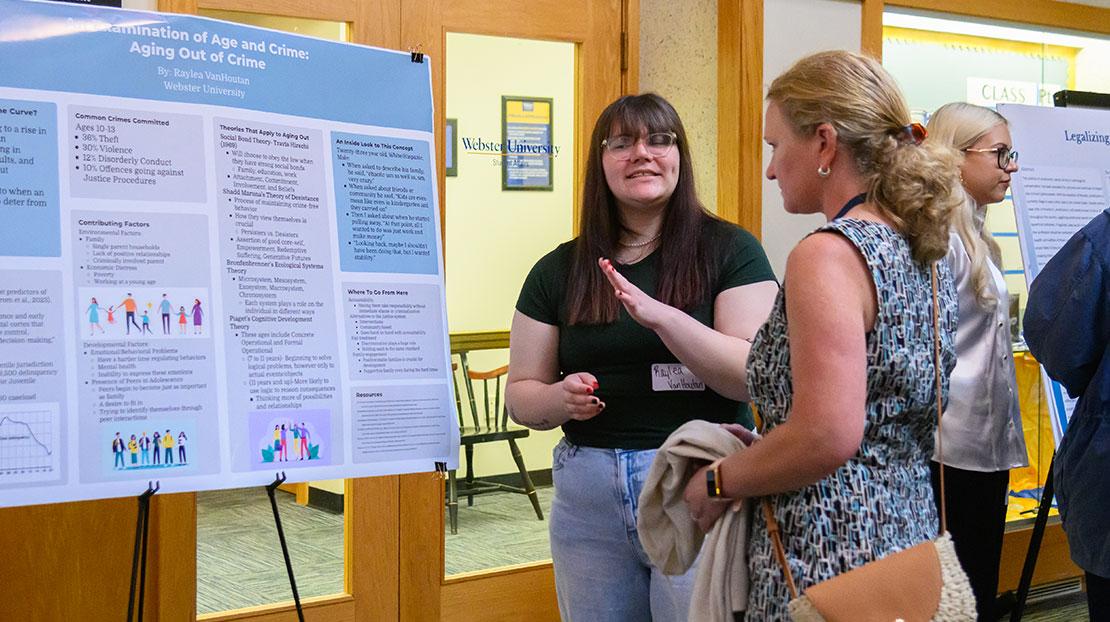 Raylea VanHoutan talks with a woman about her poster, An Examination of Age and Crime: Aging Out of Crime