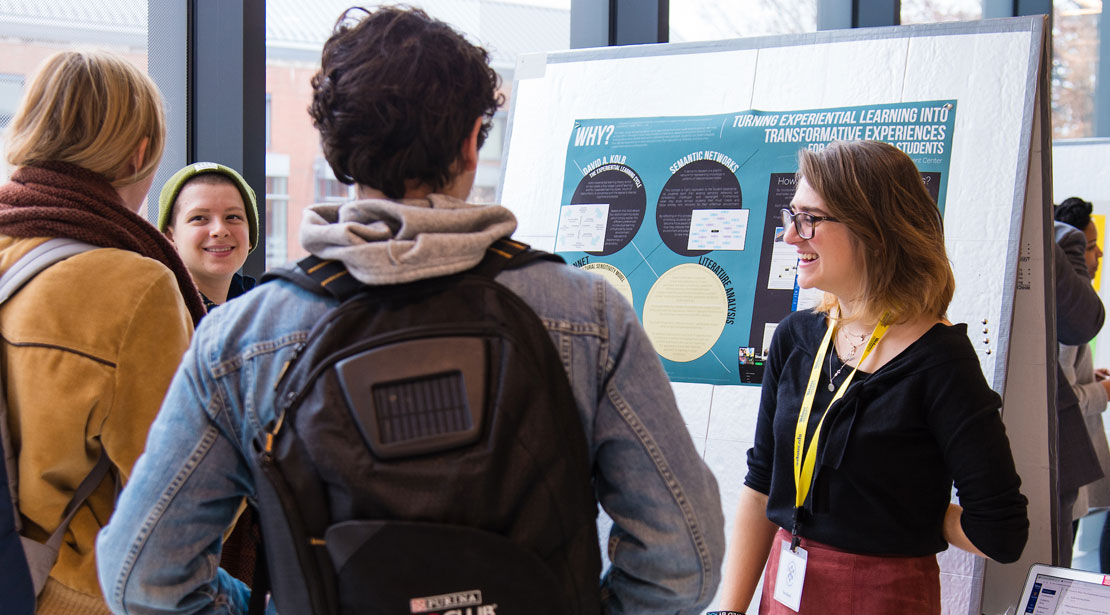 researcher presenting poster to group of students