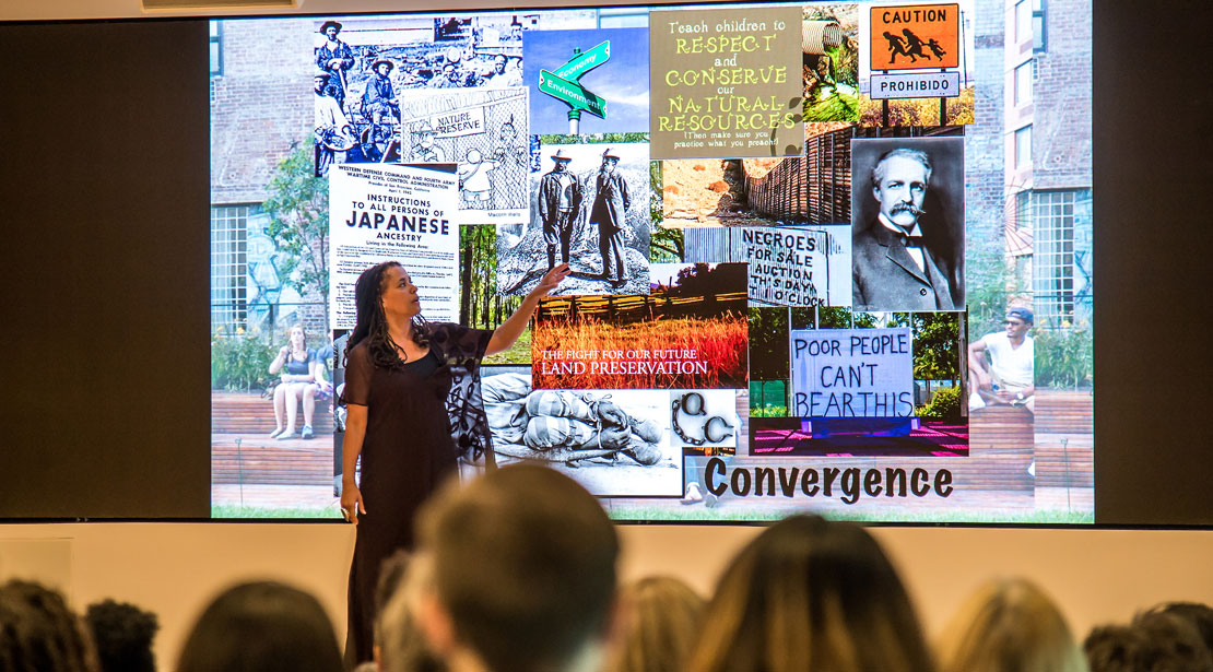 A speaker pointing to a slide of photographs