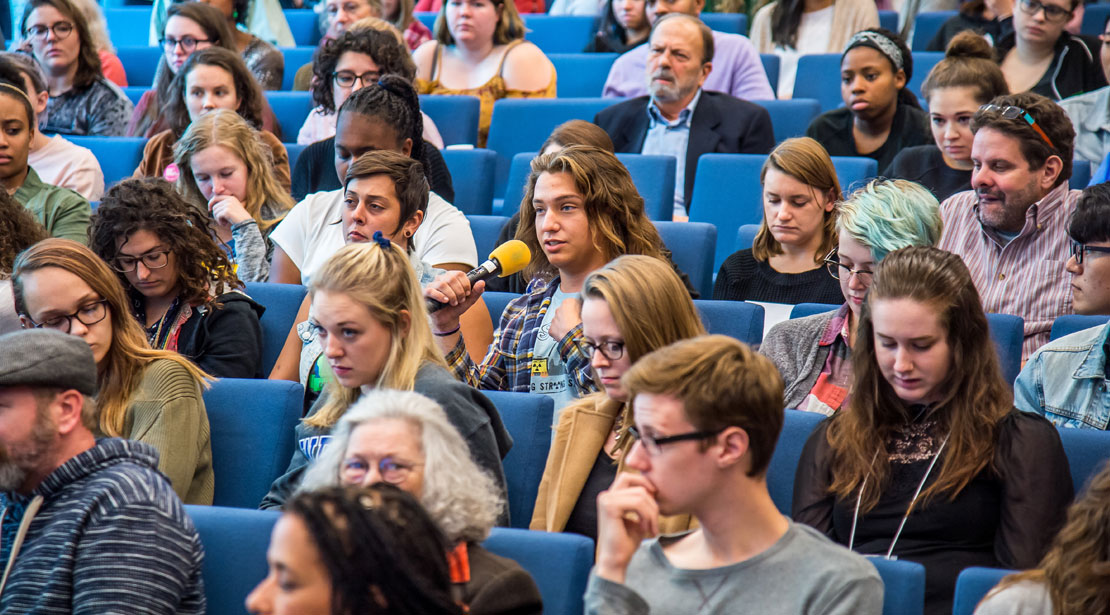 An audience member in the middle of the auditorium asking a question