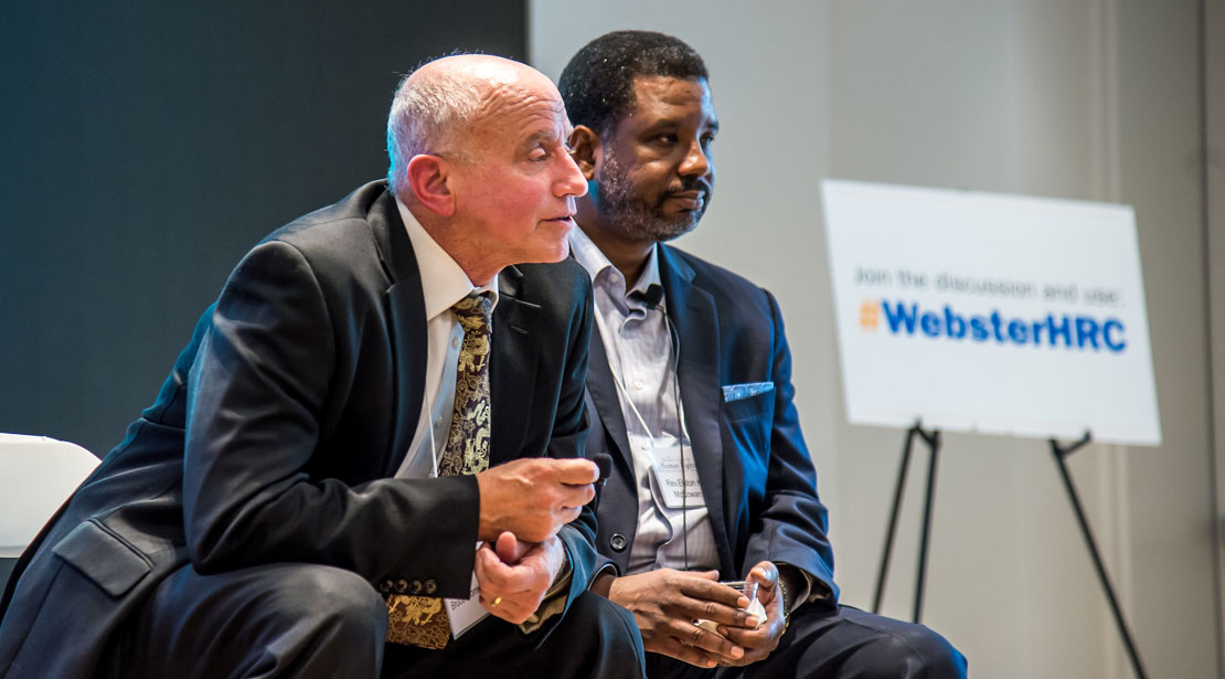 One of the panelists leaning forward while replying to an audience question