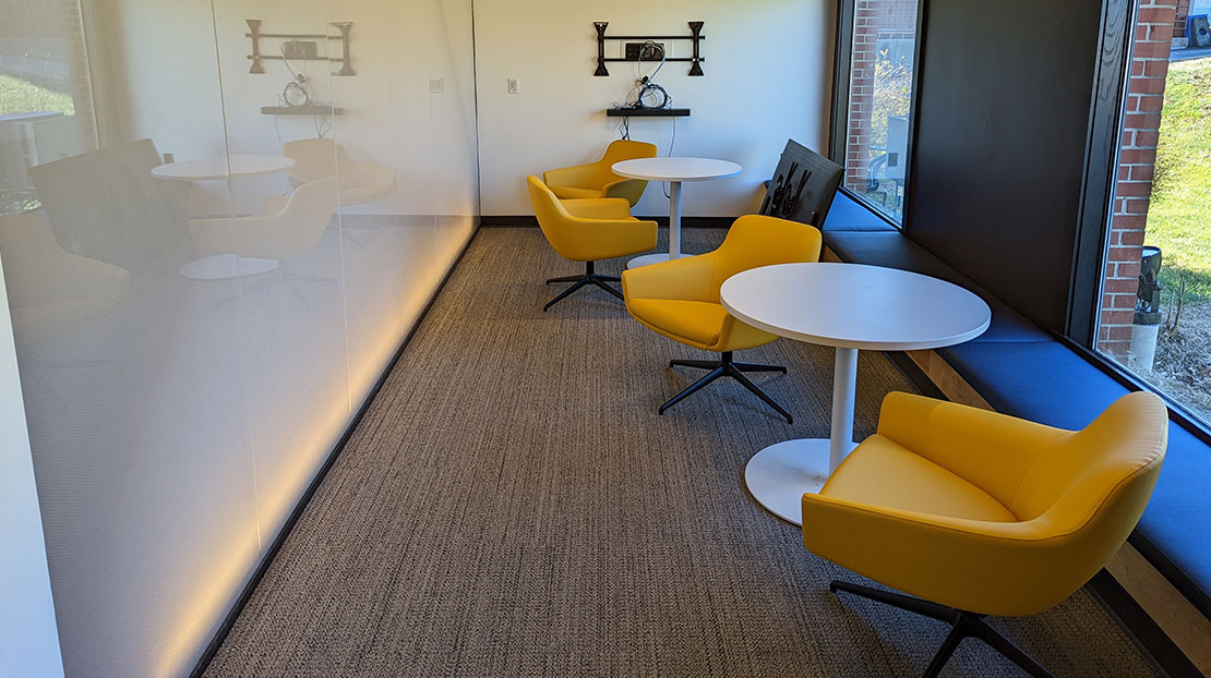 yellow chairs with white round tables in front of white board wall