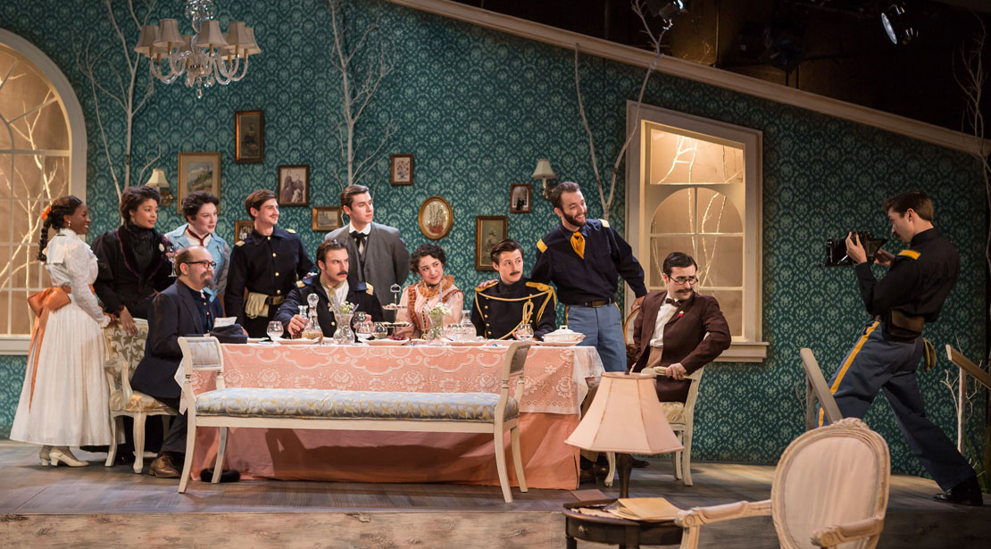 The scene in the play where the cast poses around the dining room table for a photo taken by one of the soldiers.