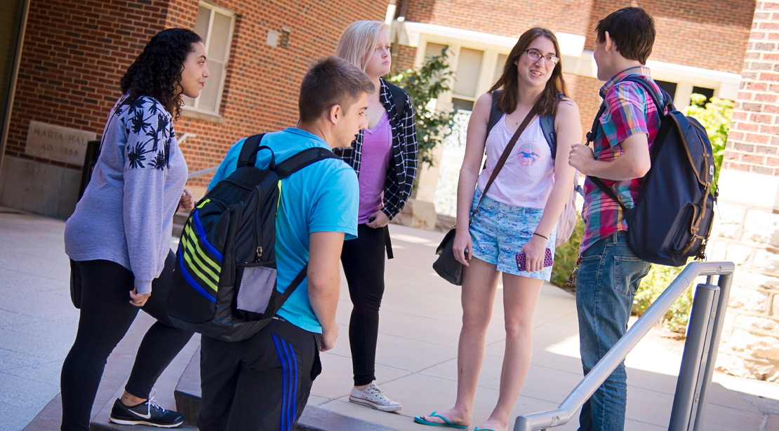 A group of students conversing on stairs in a courtyard.