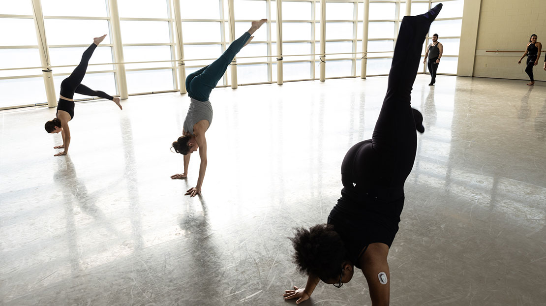 Three dancers in split leg handstands.