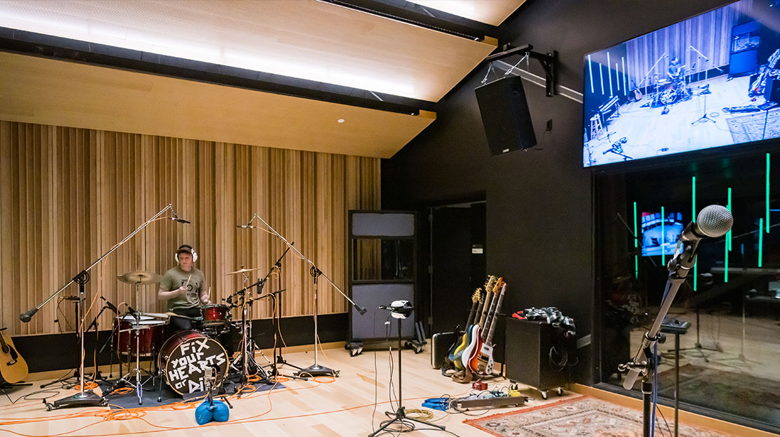 music recording room showing drummer at mic'd up drumset