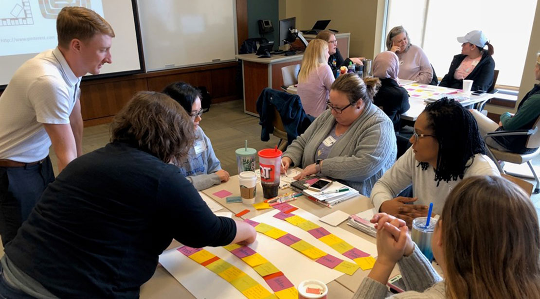 Group of students situated around a table work on a cards activity