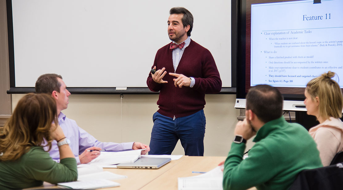 Dr. Soheil Mansouri lectures a classroom of students sitting at tables