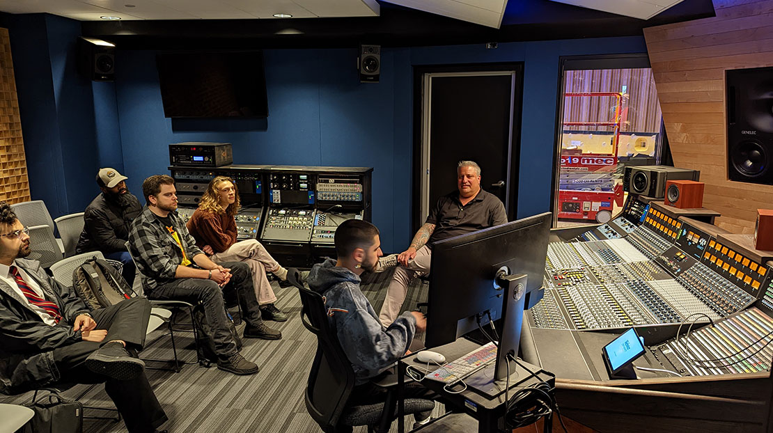 students and professor in classroom with AXS Legacy audio production and mixing board