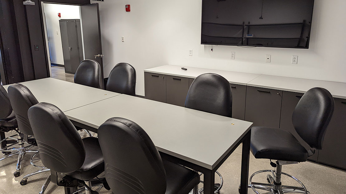 workshop room with roll chairs, long table and TV monitor