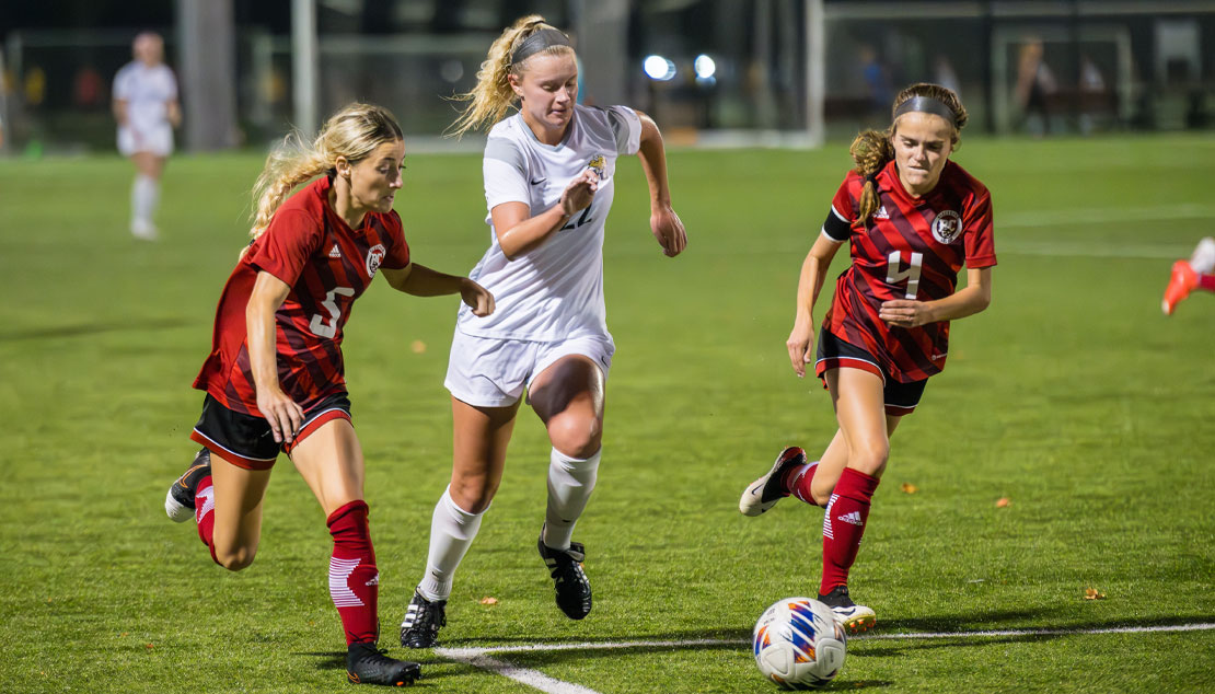 A female student races against opponents to get the soccer ball