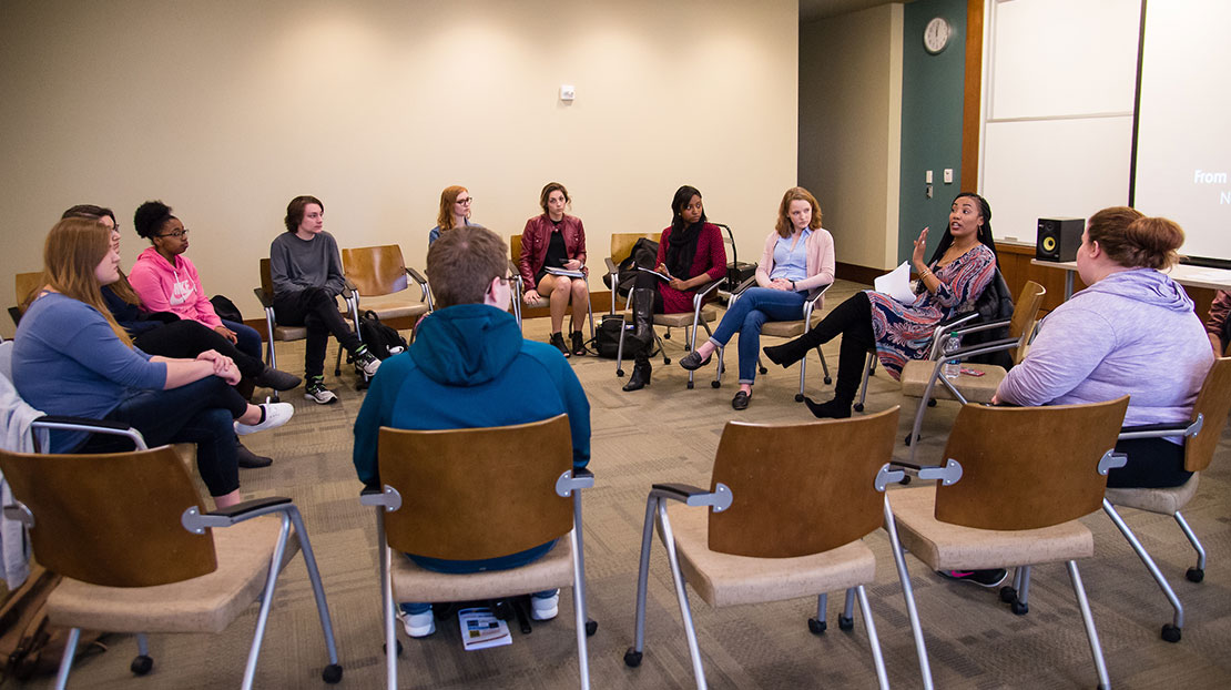 Students and workshop presenter sit in large circle for discussion