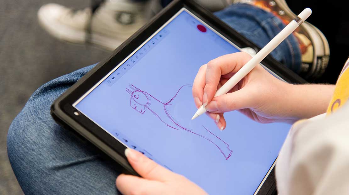 A students uses a stylus to create an animated figure on a tablet.