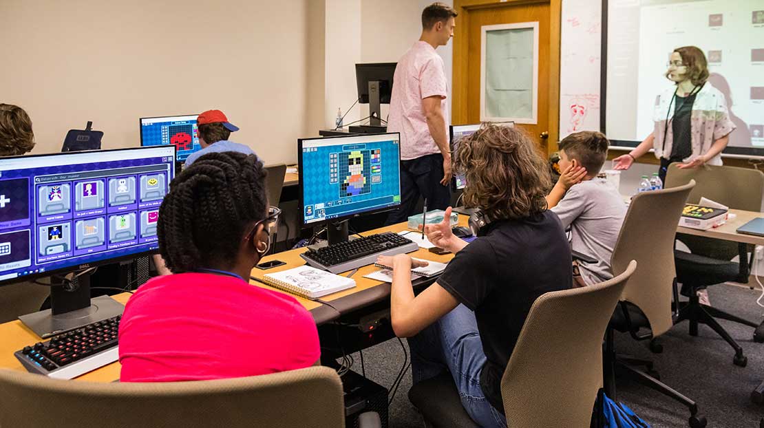Classroom with students, a professor and several computers for game design.