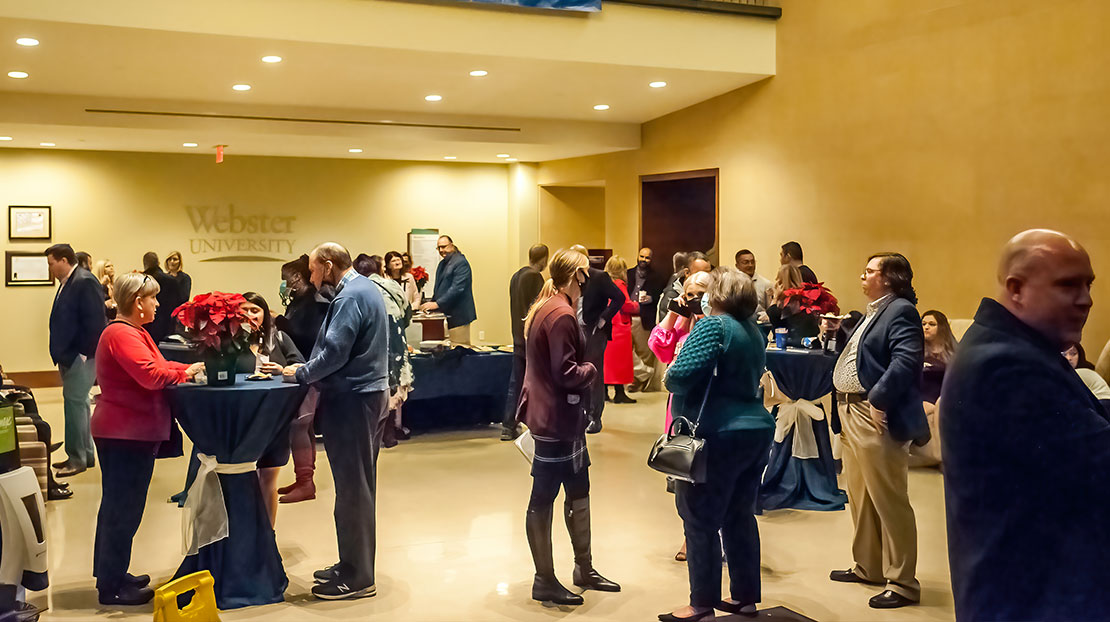 Small groups of people gather around standing tables to talk