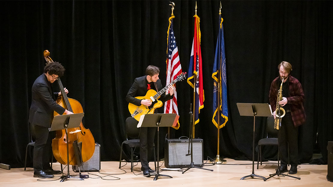 Bass player, guitarist and saxophonist perform on stage