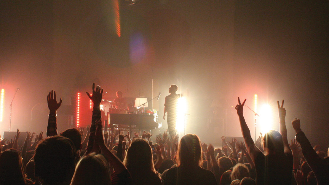 A giant crowd dancing with their hands in the air during a concert.