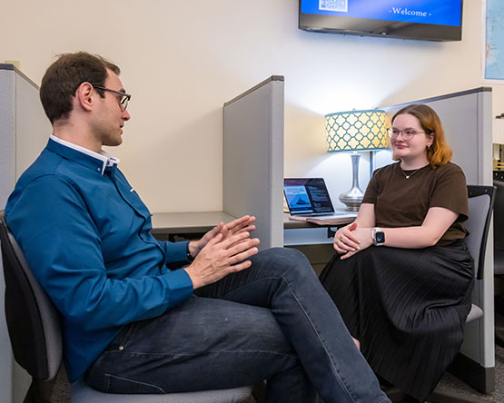 Dani Belo sits with research assistant Samantha Ramay at lab cubicle desk