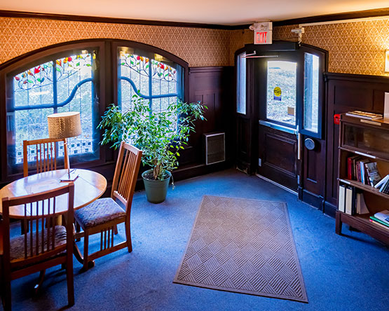 Entryway filled with dark wood, stained glass windows and table with chairs