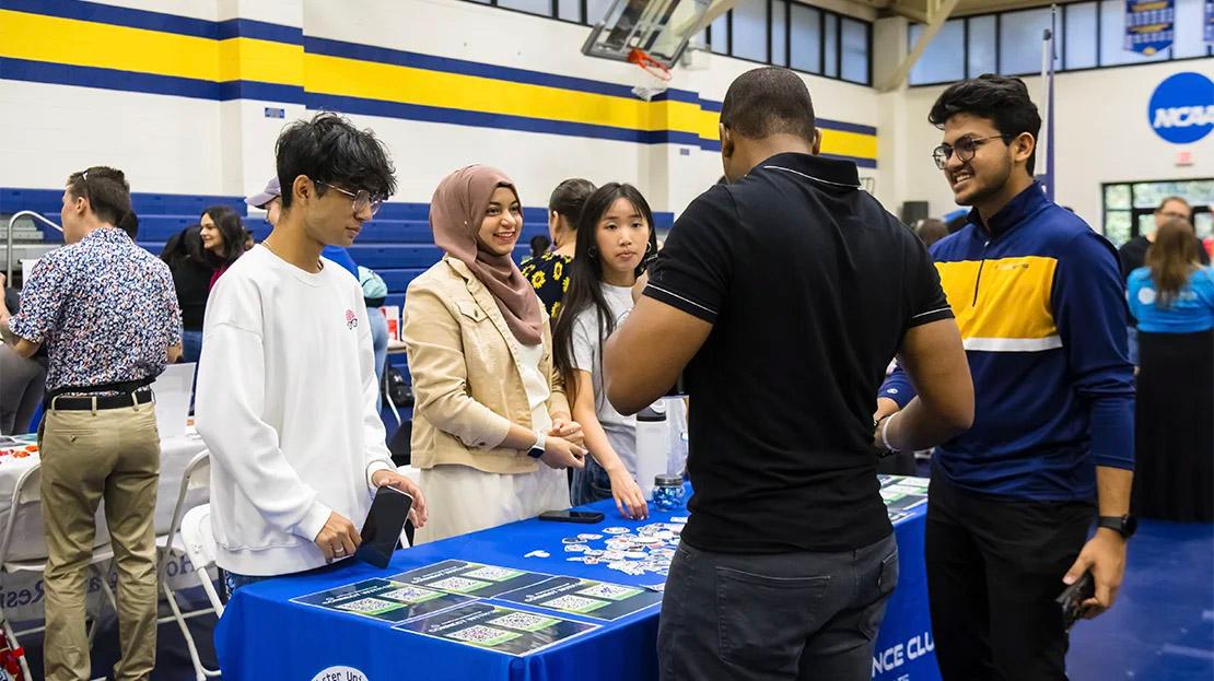 Students visit a table at a campus involvement fair event. 